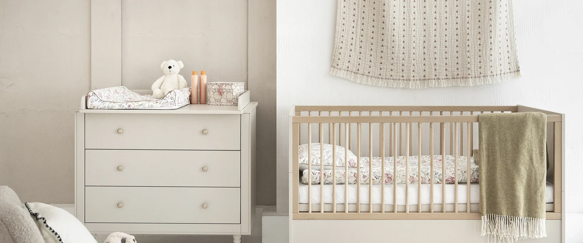 Zdjęcie lifestyle (aranżacja) z kolekcji Petite w kolorze champagne przedstawiające zestaw mebli do pokoju niemowlęcego: łóżeczko niemowlęce z szczebelkami oraz komodę z trzema szufladami