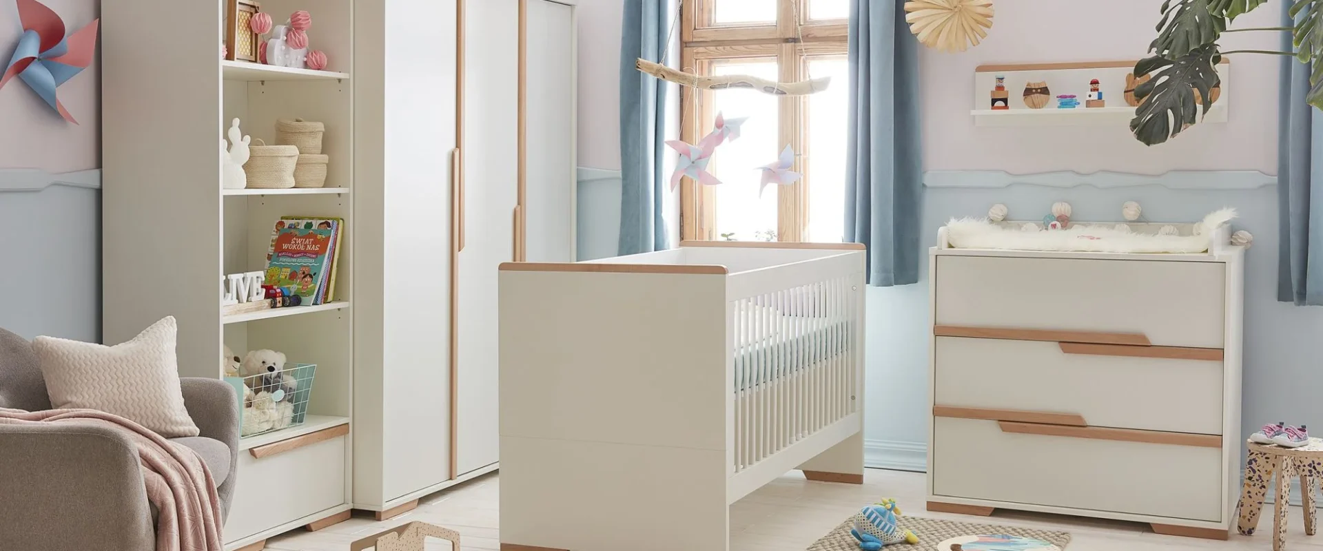 Zdjęcie lifestyle przedstawiające zestaw mebli niemowlęcych z kolekcji Pinio w kolorze białym z wykończeniem w naturalnym drewnie