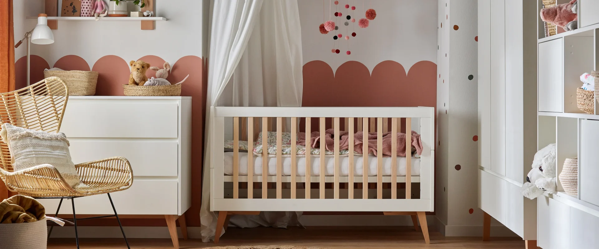 Łóżeczko niemowlęce z kolekcji Swing White, kolor biały z drewnianymi nóżkami, standardowy rozmiar, zdjęcie lifestyle (nie packshot) przedstawiające mebel w urządzonym pokoju